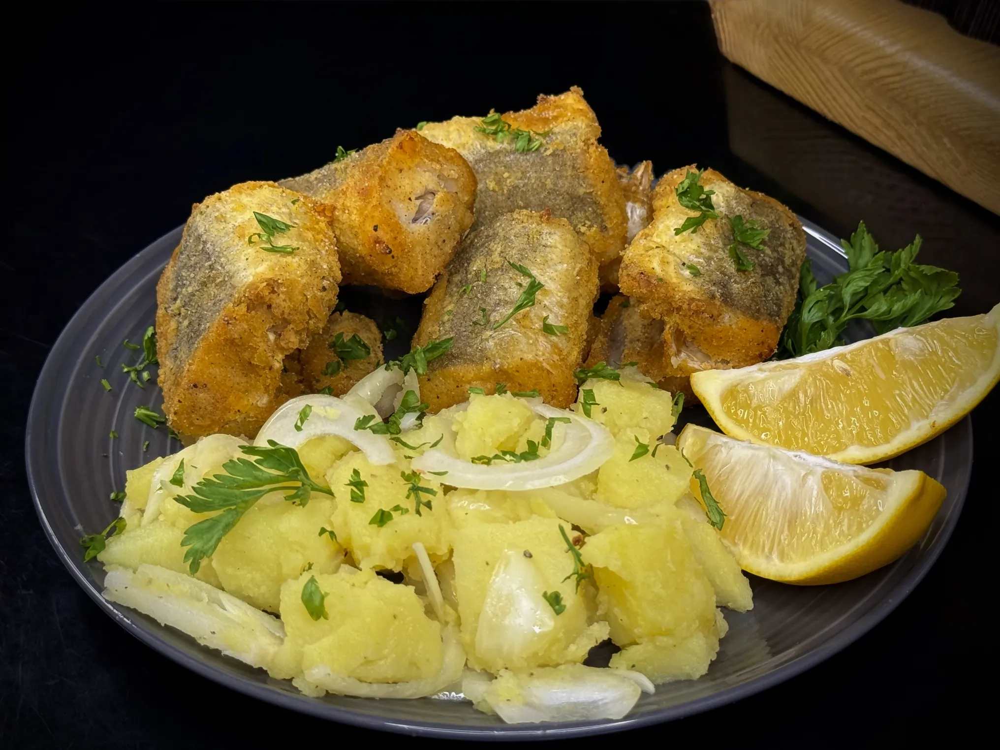 Zlatno pečeni oslić iz rerne sa kukuruznim brašnom, serviran sa krompir salatom i kriškom limuna, savršen za posno jelo.