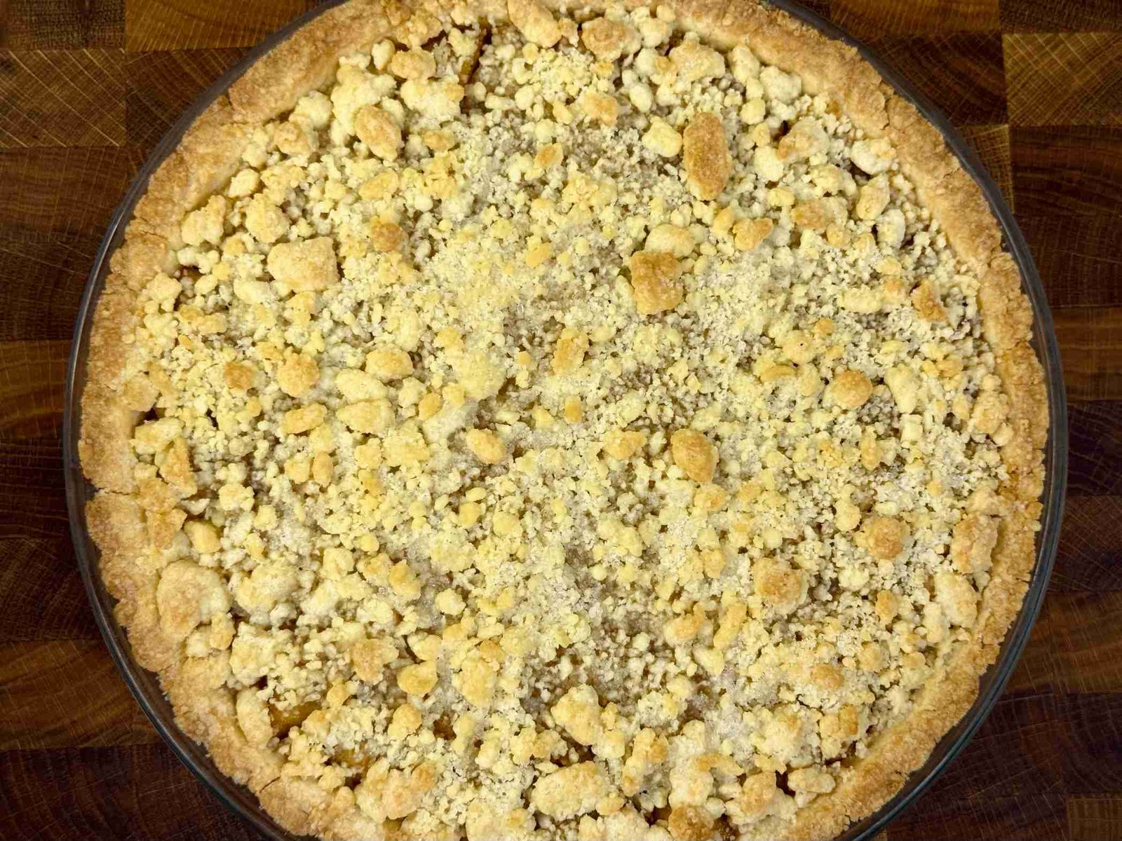 Zlatno pečen tart od jabuka sa hrskavom koricom od mrvica, slikan odozgo na drvenoj podlozi.