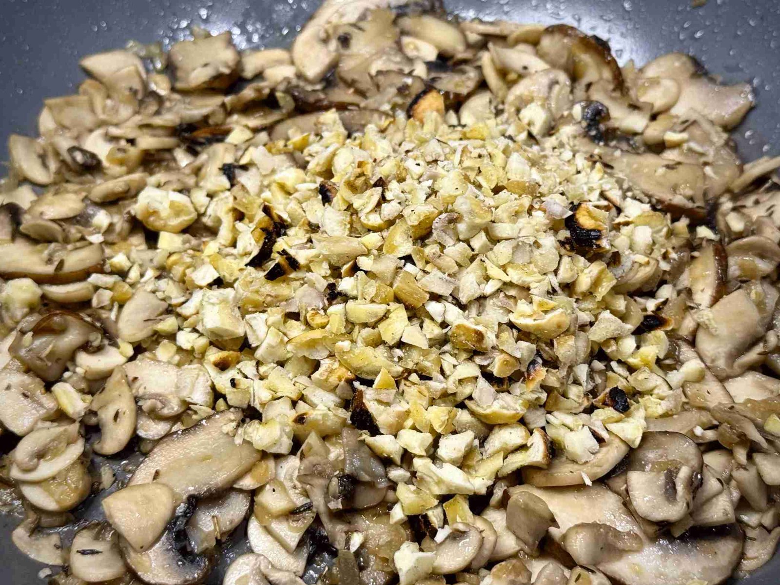 przene-gljive-kesten Sjeckane pržene gljive (šampinjoni) i pečeni kesten u tiganju, spremni za zalijevanje temeljcem za sos.