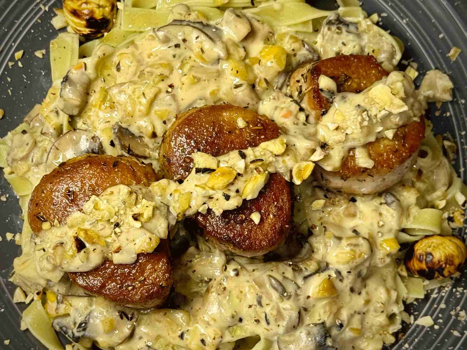 Svinjski file u kremastom sosu od gljiva i kestena, serviran na tanjiru sa taljatelama.