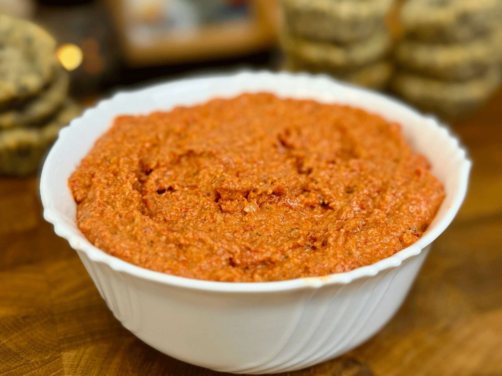 Kremasti, narandžasti fil od pečene paprike i oraha u bijeloj keramičkoj posudi.