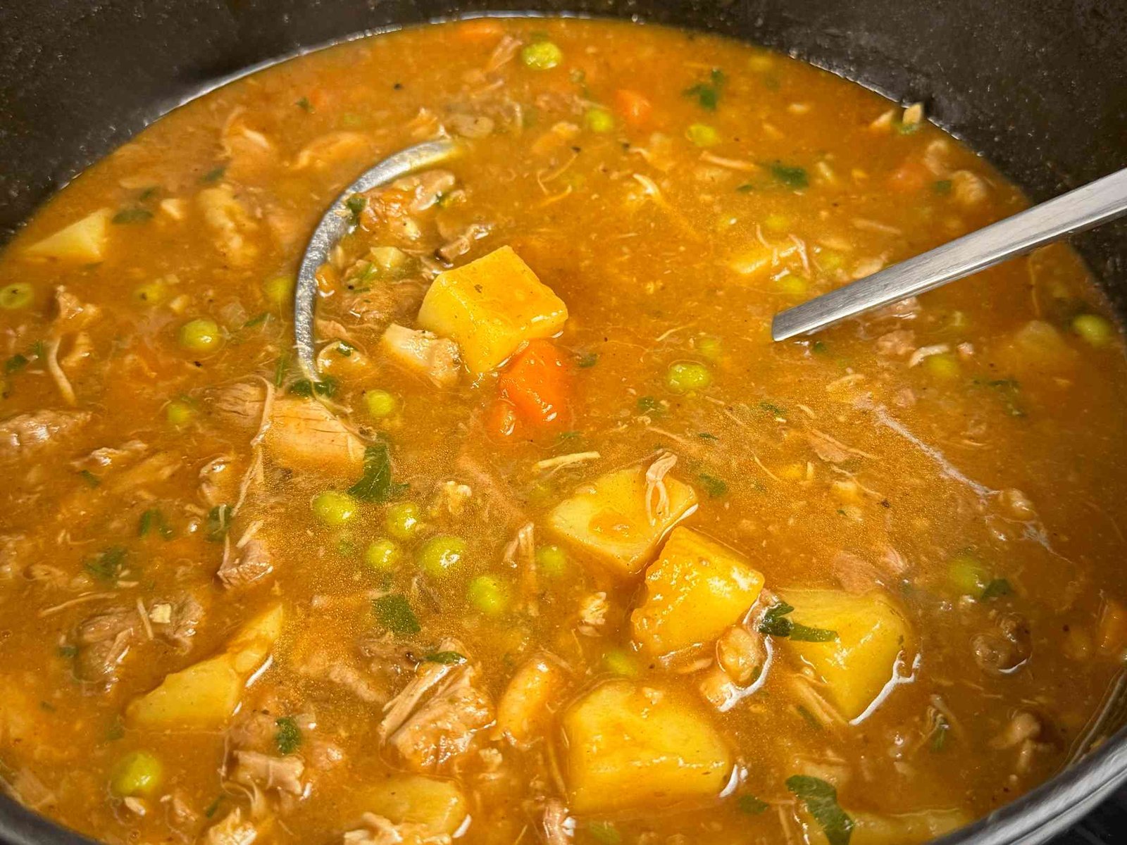 Gotova, gusta čorba sa tri vrste mesa i povrćem u crnom loncu, miješanje kutlačom prije serviranja.