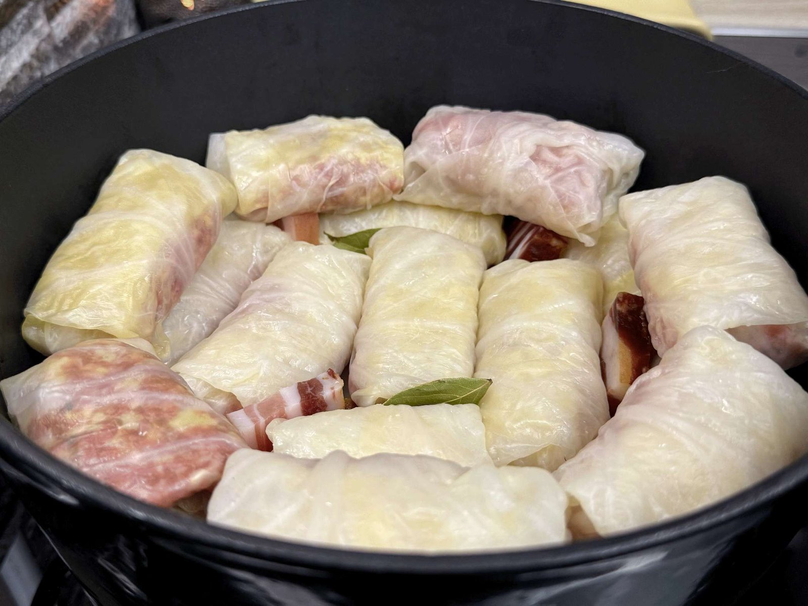 poredana-sarma-u-serpi Sarme gusto složene u lonac sa parčićima slanine i lovorovim listom, spremne za kuhanje.