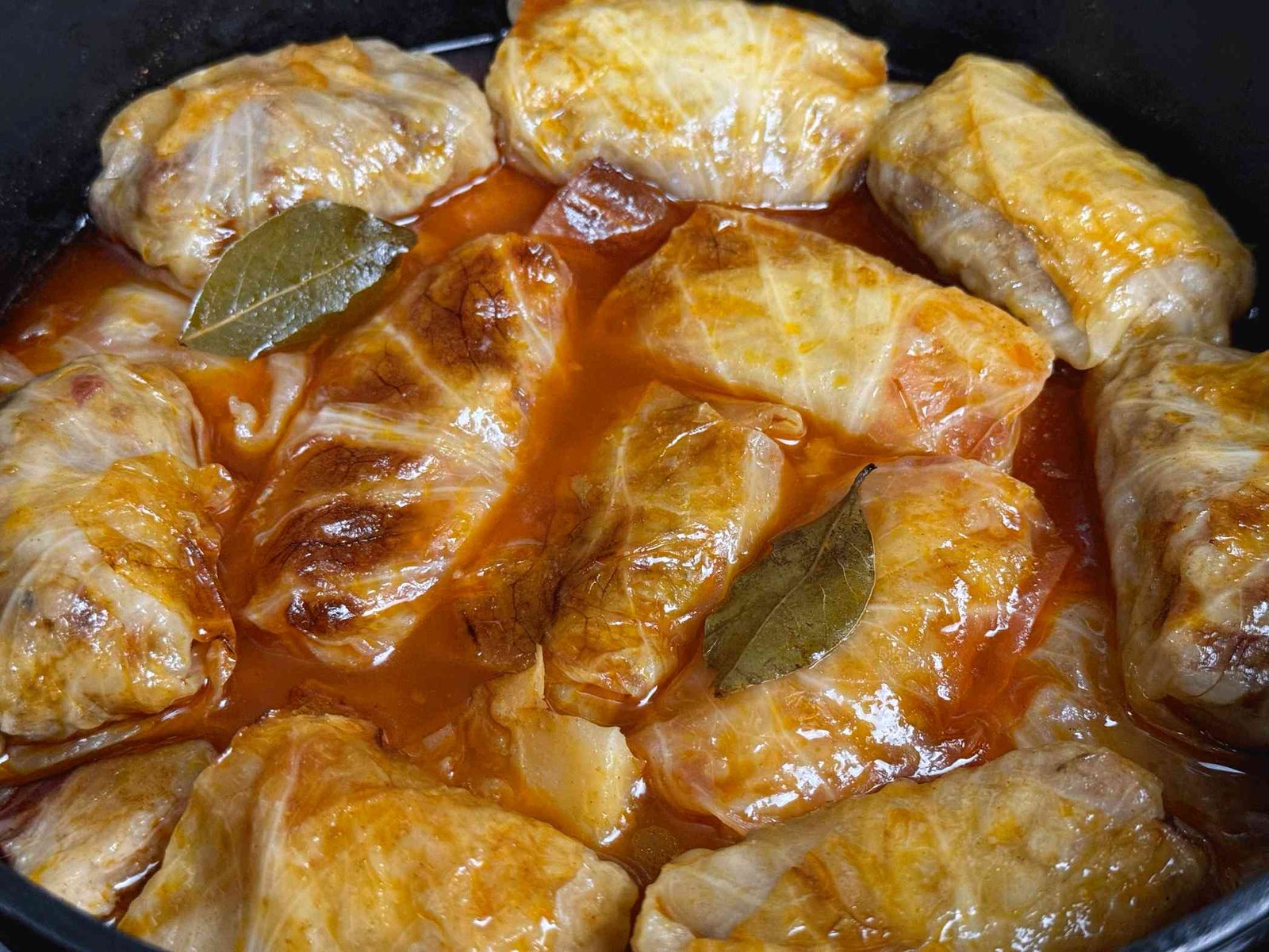 sarma-kupus-slanina Gotova sarma sa kiselim kupusom, skuvana i zapečena, u loncu, sa sočnim umakom i lovorovim listovima.