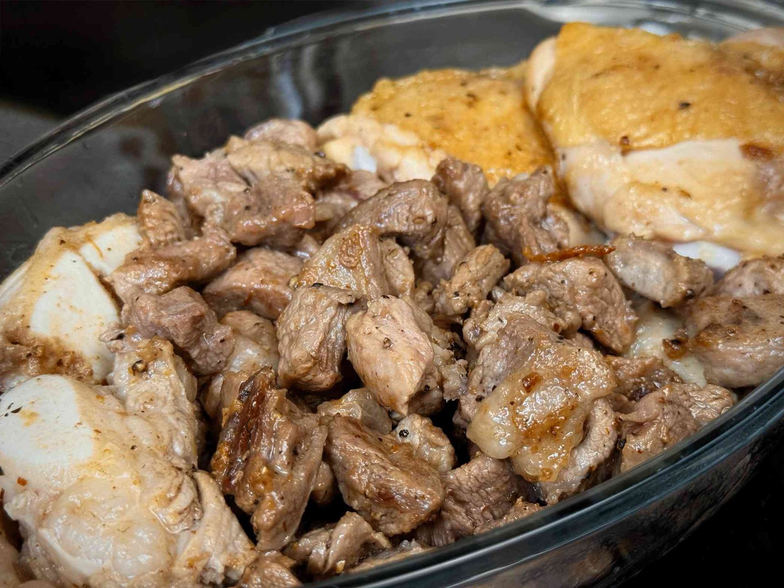 Zapečeni komadi svinjetine, junetine i piletine u staklenoj posudi, nakon prvog pečenja za dublji ukus.