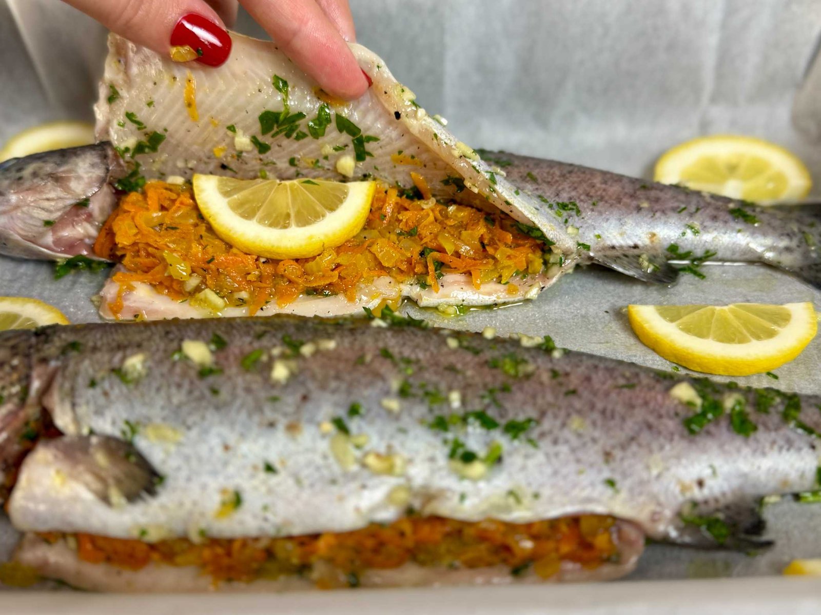 Punjenje očišćene pastrmke dinstanom mrkvom, lukom i kolutom limuna.