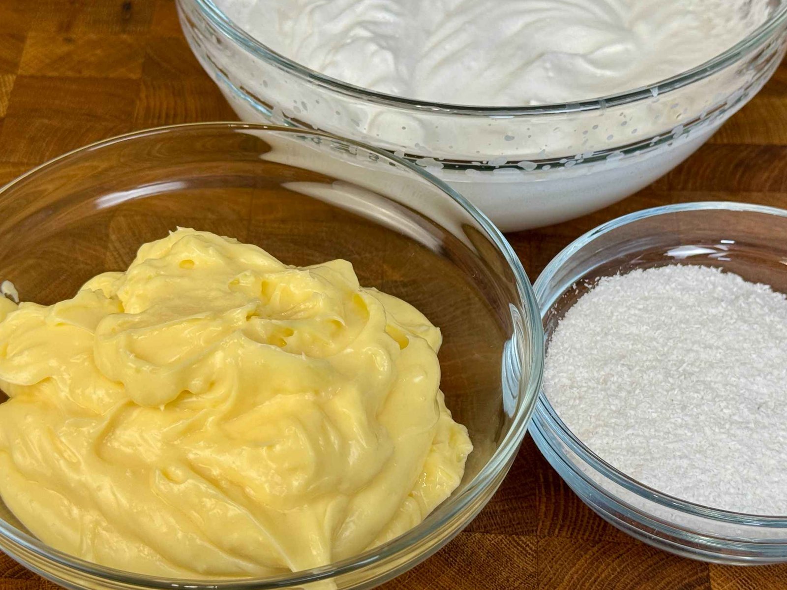 Tri staklene činije: puding od vanilije, umućena halta i kokosovo brašno.