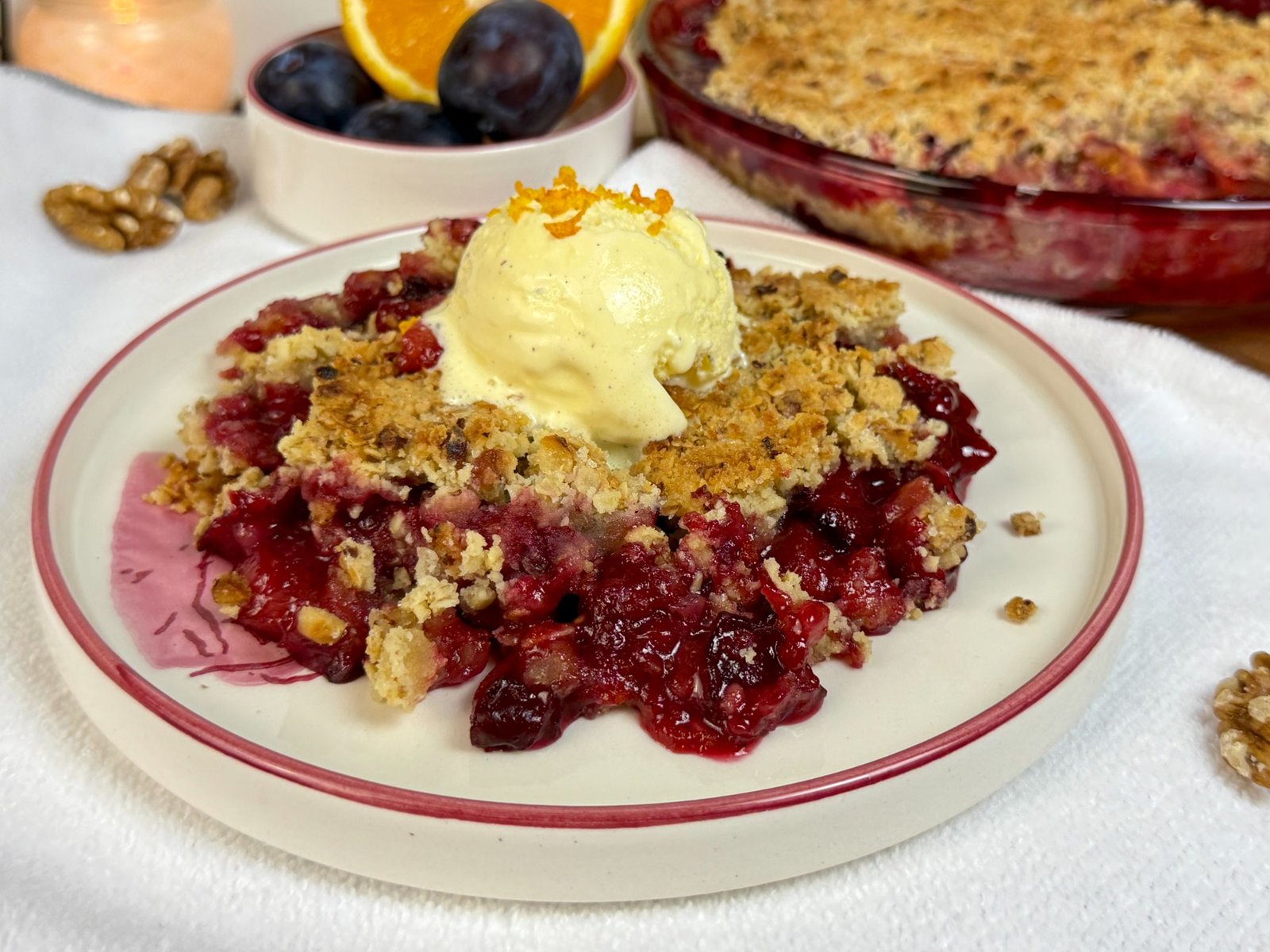 Crumble sa šljivama, narandžom i cimetom, serviran iz kuglu sladoleda od vanilije